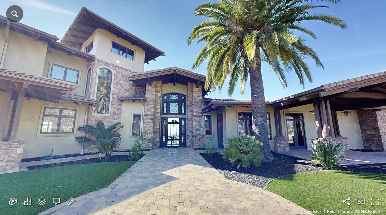 Matterport 3D tour view of a luxury home front entry with stone columns and a palm tree